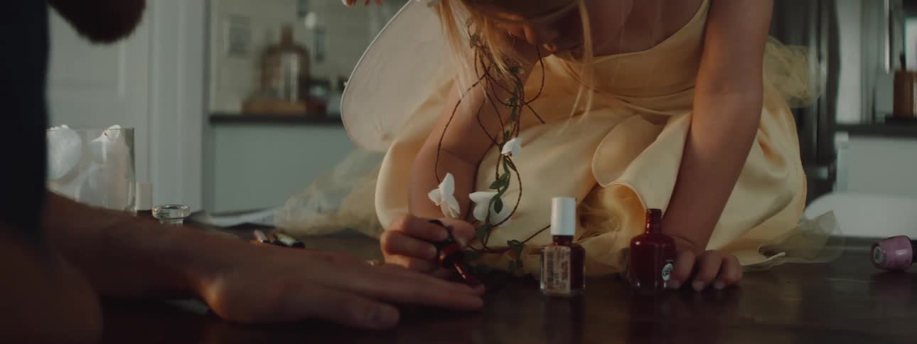 A young girl at home paints her dads nails