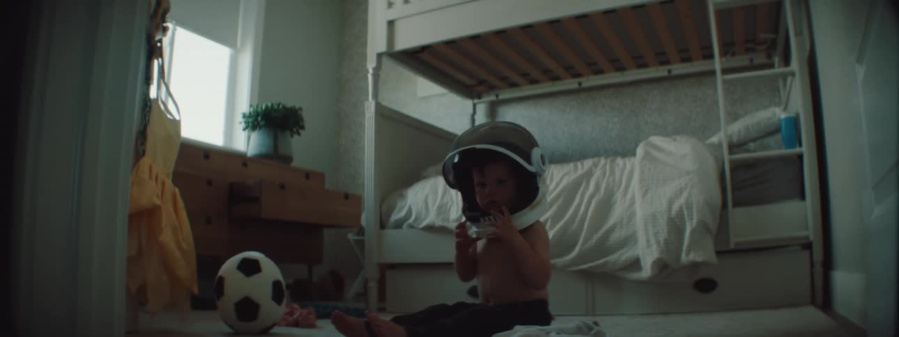 Toddler playing with an astrounaut helmet in a room at home