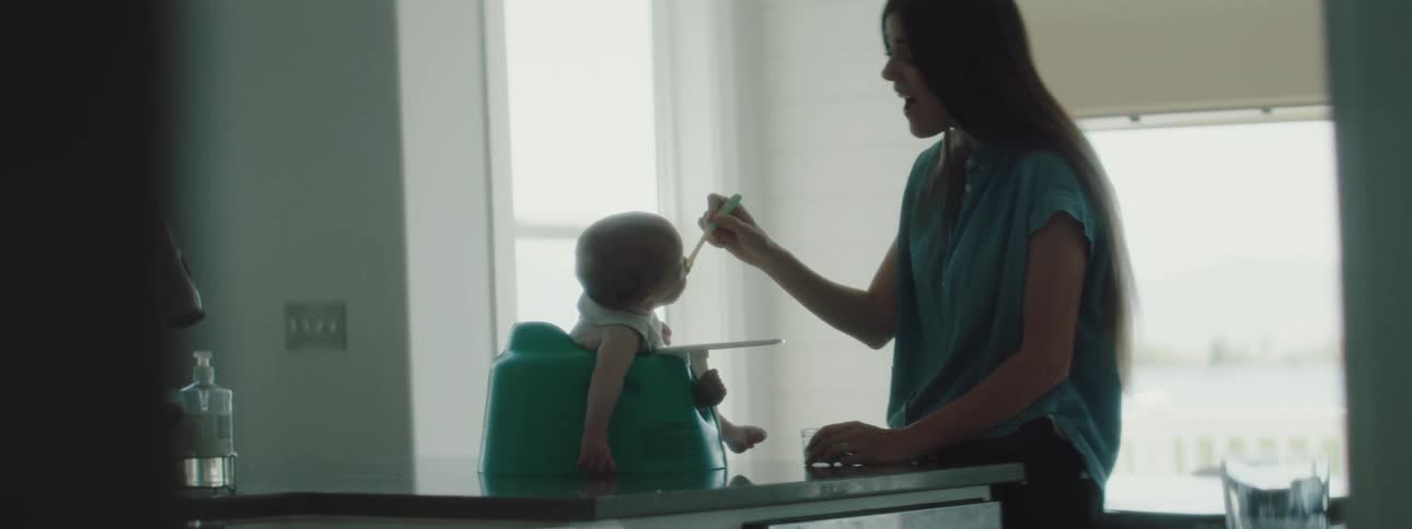 A mother is feeding her baby in the kitchen