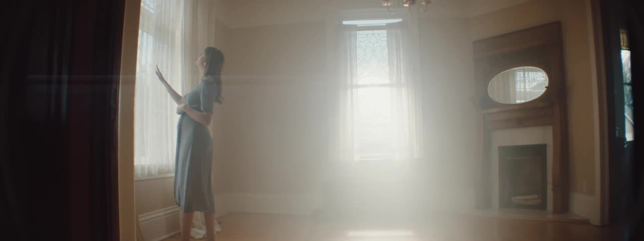 A pregnant woman is standing in an empty room
