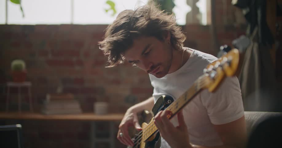 A man is sitting on a chair and playing the guitar