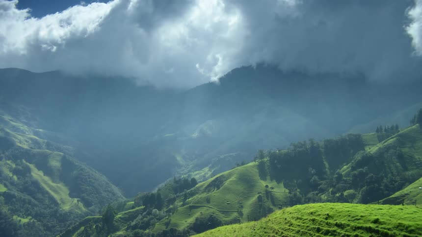 Clouds rolling over the green slopes of a mountain range