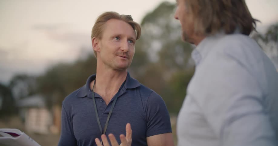 Two men talking on a field in the countryside at evening