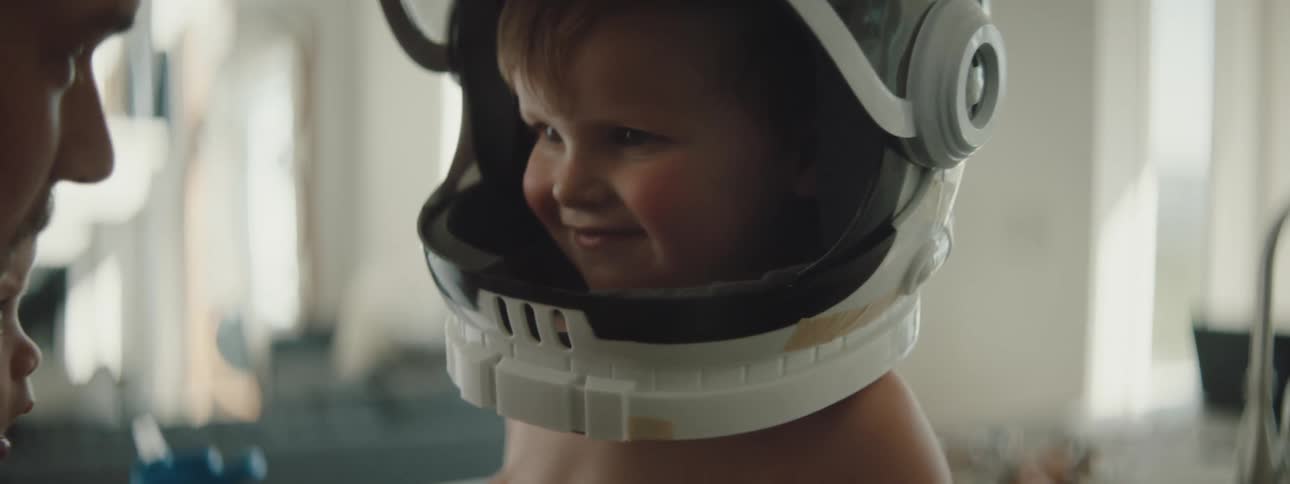Shirtless boy playing with an astronaut helmet at home