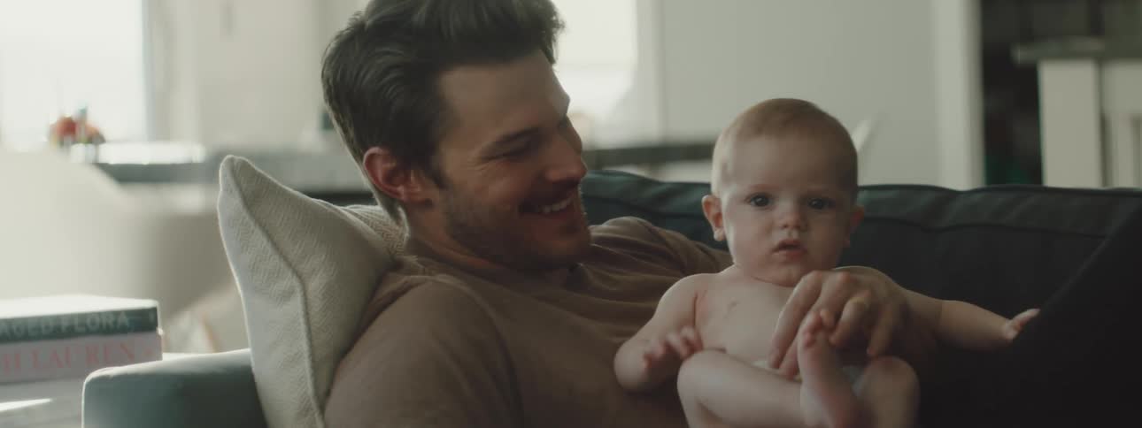 A man holds his baby on the couch