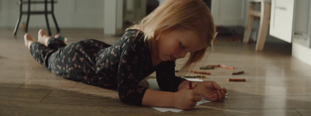 A child is drawing on a piece of paper indoors