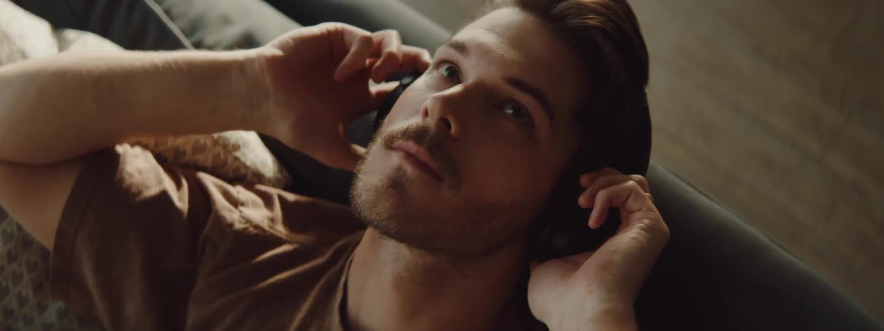 Man with a beard wears a black headphones to listen to music
