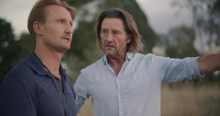 Two men are talking outdoors in a rural area