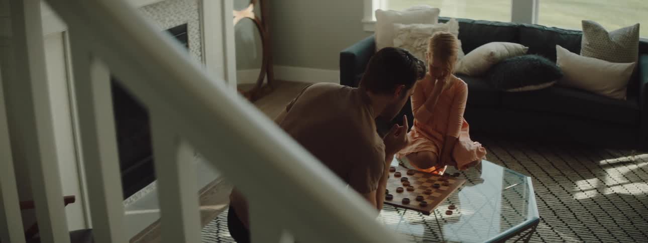 A man and a girl in a room playing checkers on a table