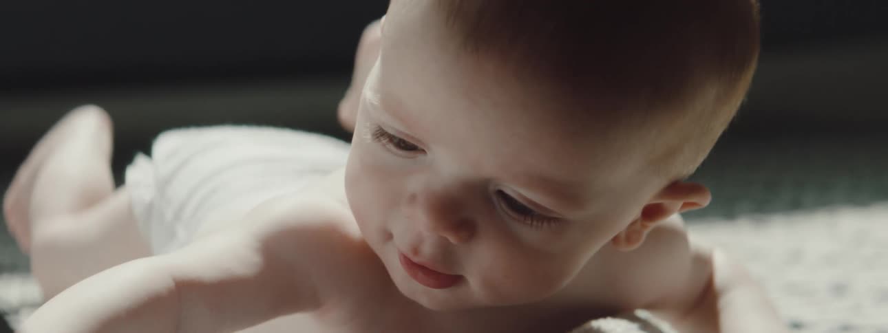 A baby with diapers crawling on a blanket on the floor