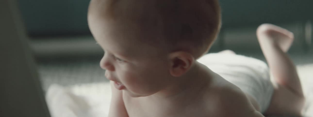 A baby lying on its back on a blanket on the floor turns over to lay on their stomach