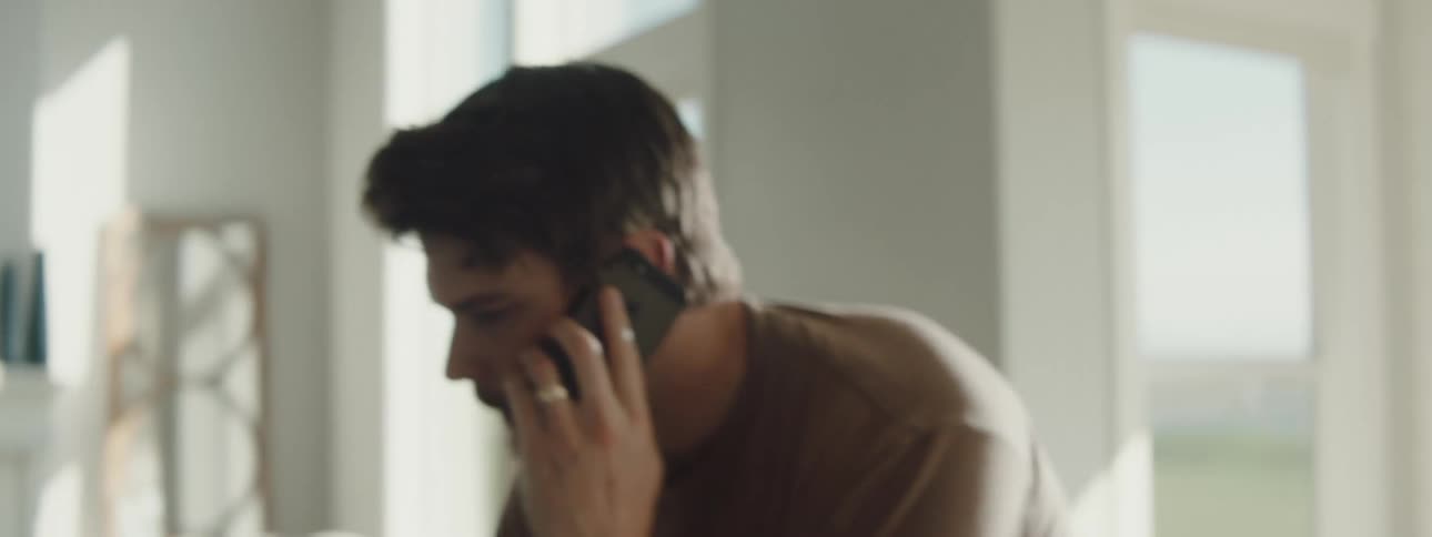 Man talking on the phone moves around the living room to take notes
