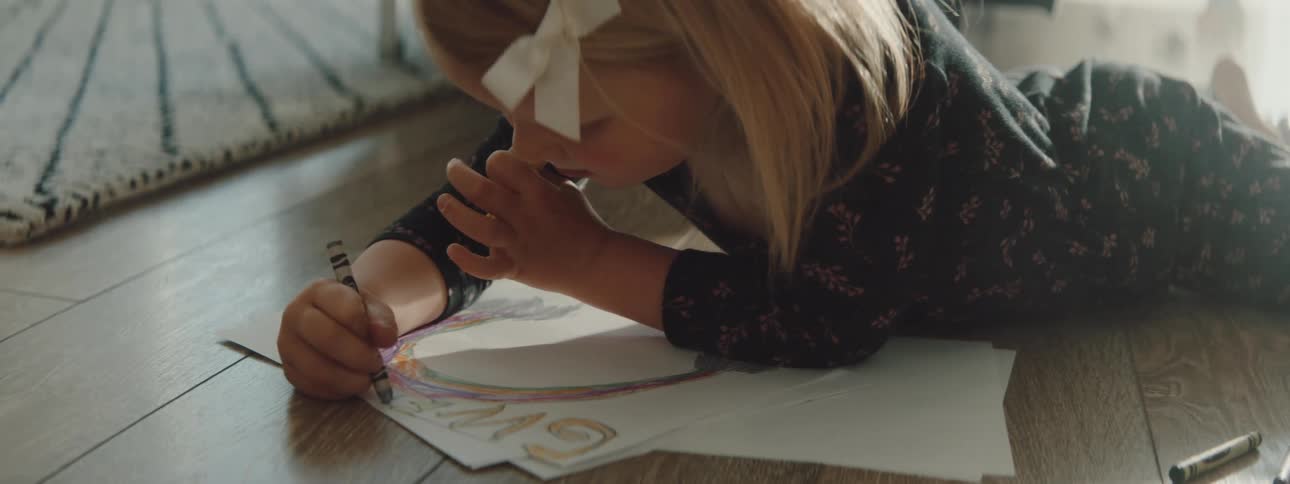A girl is coloring on the living room floor