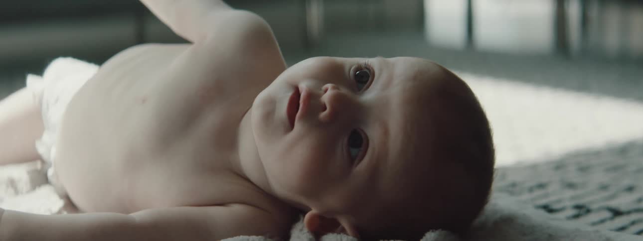 A baby with a diaper crawling on a blanket on the floor in a room