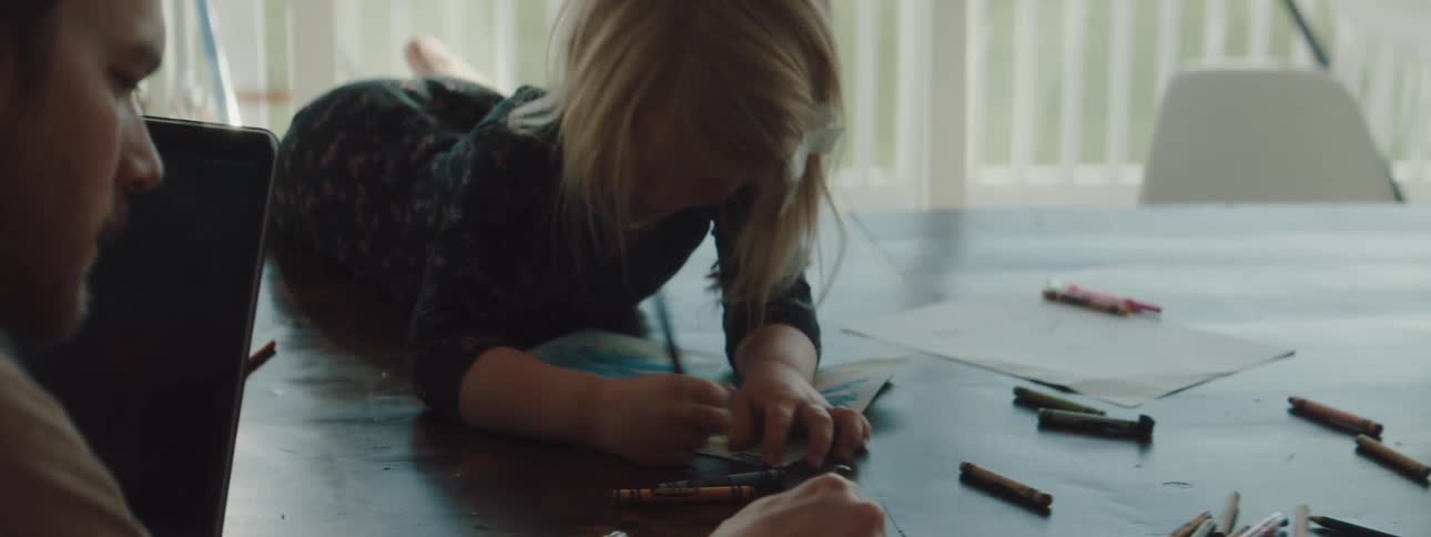 Father playing with daughter drawing with crayons over a table