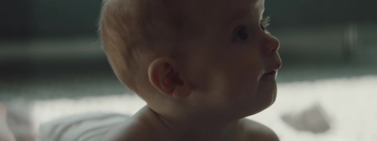 A baby with a diaper crawling on a blanket on the floor in a room
