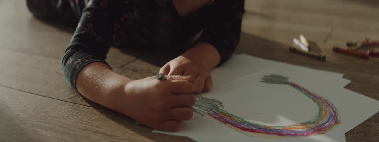 A little girl lies on the floor at home and colors