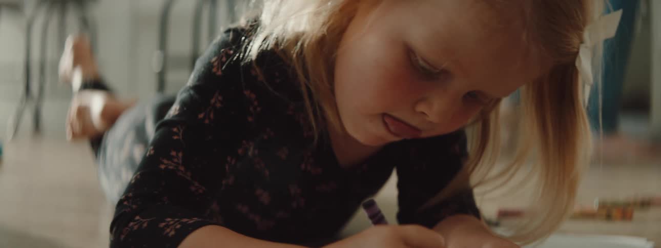A child is drawing with crayons inside of a house