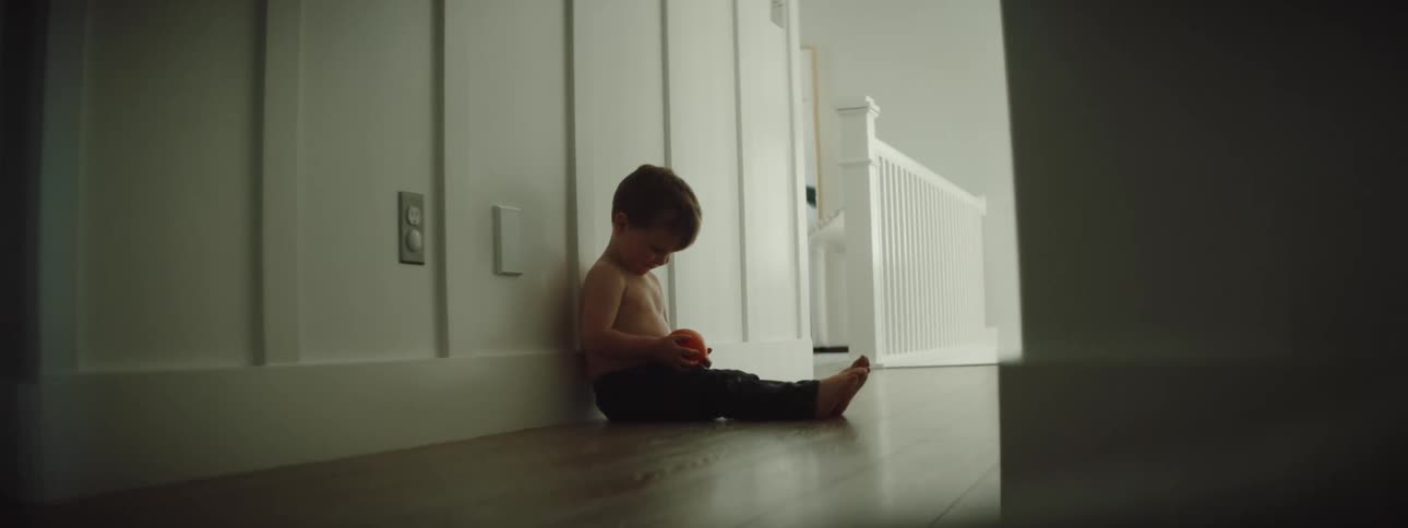 A child is playing indoors and sitting on the floor
