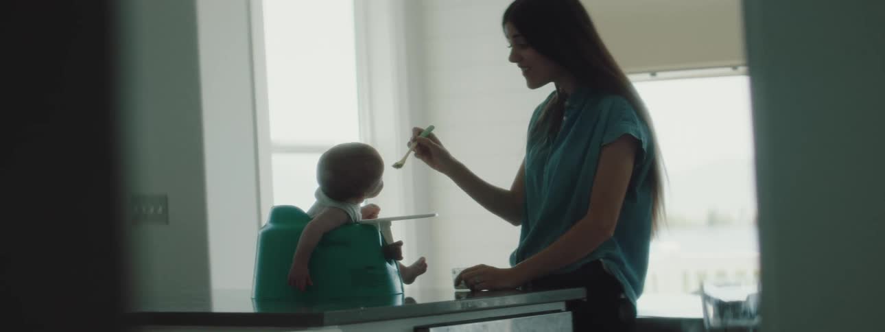 A woman at home feeds her young baby