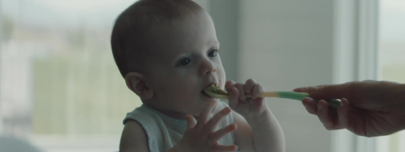 Baby eating a spoonfull of baby food at home