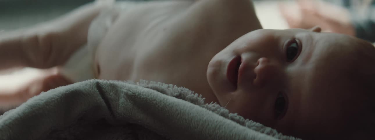 A baby is crawling on a blanket indoors