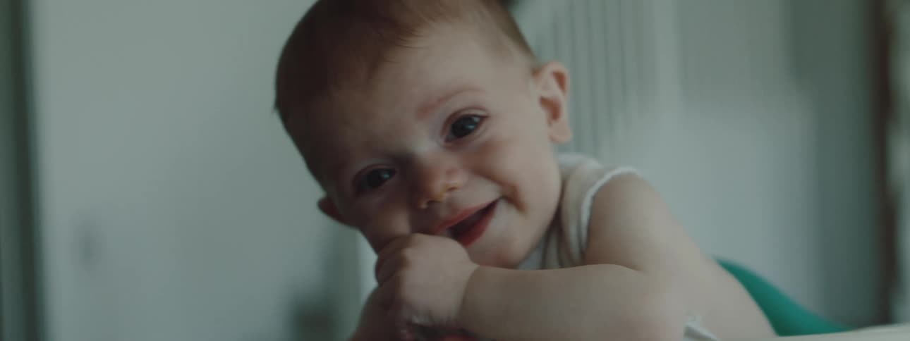 Baby sitting on a tall chair smiles while looking at the camera