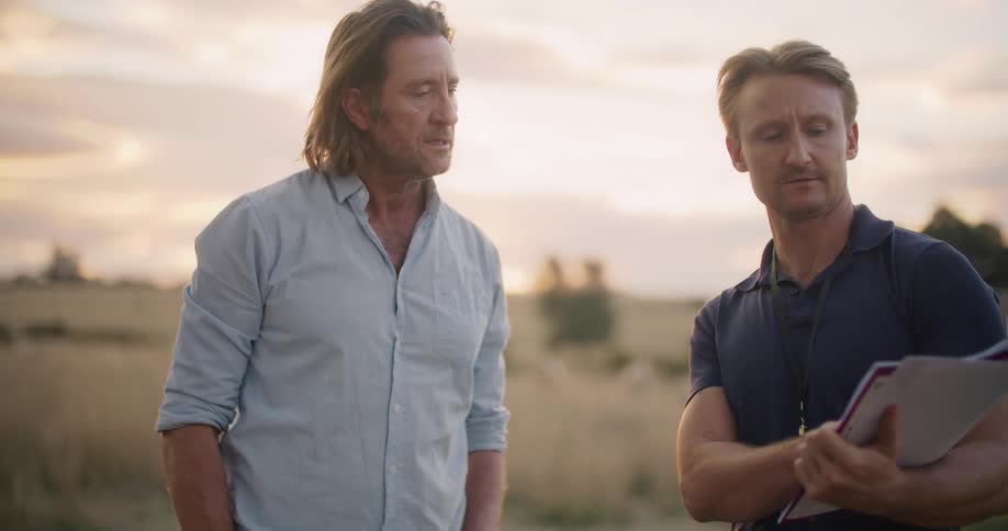 Two men talking on a field in the countryside at evening