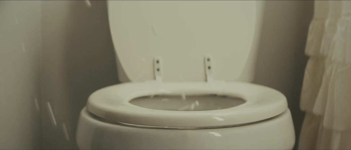 White marbles bouncing over an toilet with an open seat inside a bathroom