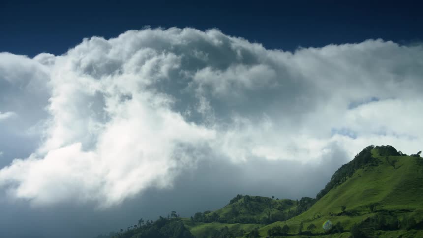 Grass covered mountain hills with clouds moving across the sky