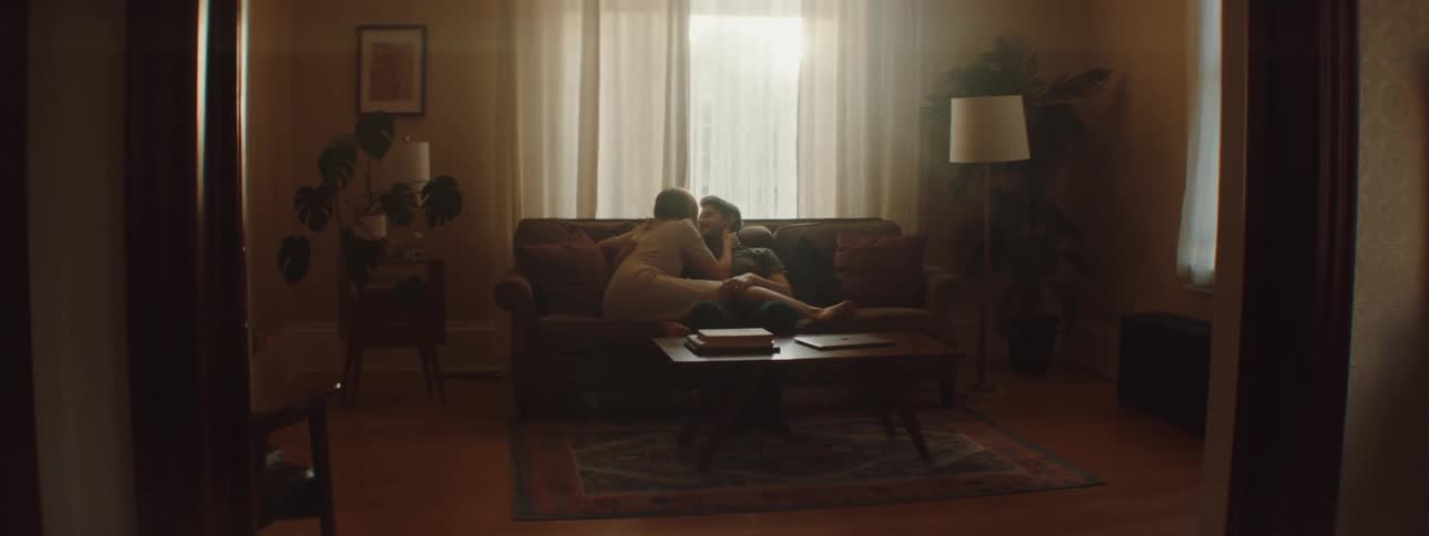 Man and woman sitting on the couch kiss each other in the living room at home