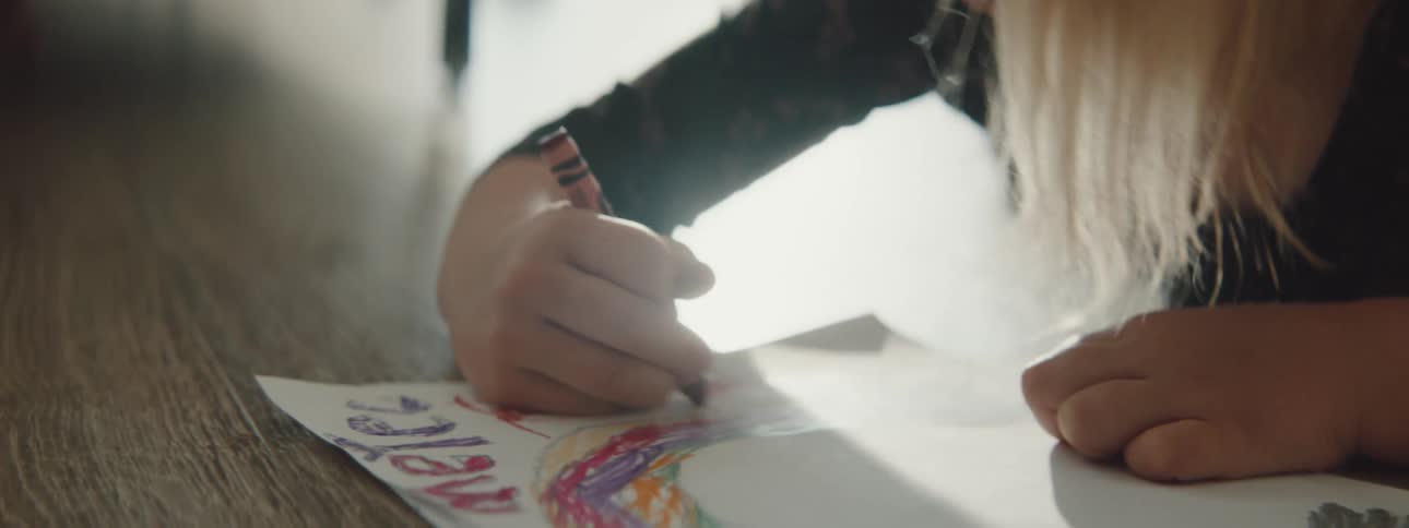 A girl is drawing on paper in the living room