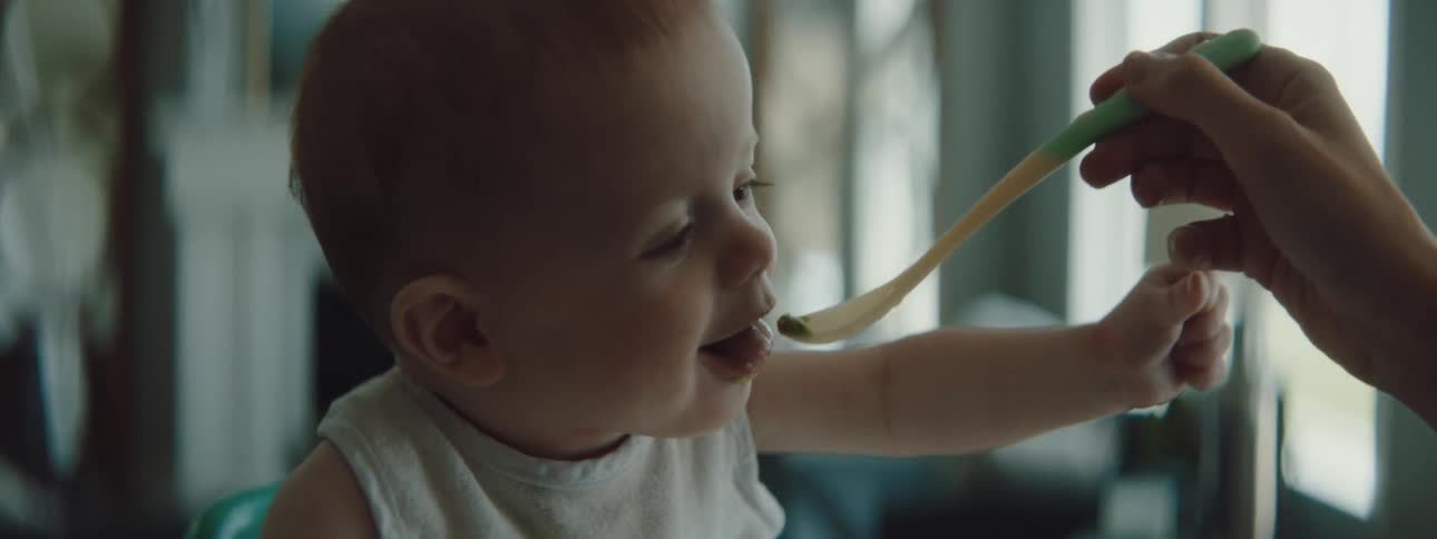 A woman spoon feeds a baby