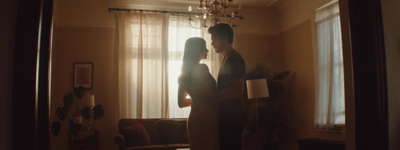 A man and woman slowly embrace each other standing in a living room