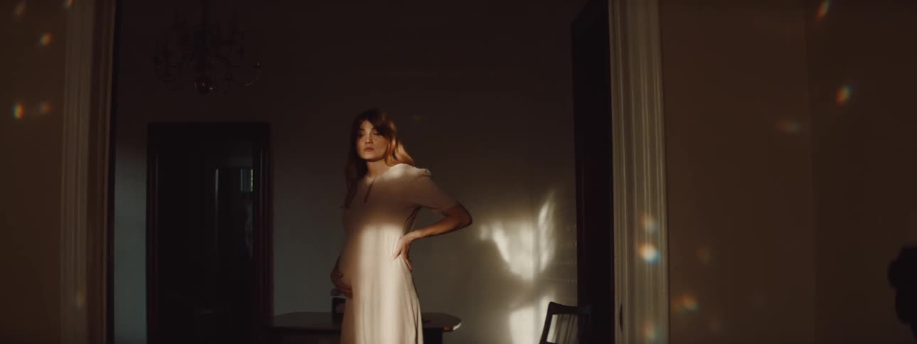 A pregnant woman is walking around her house