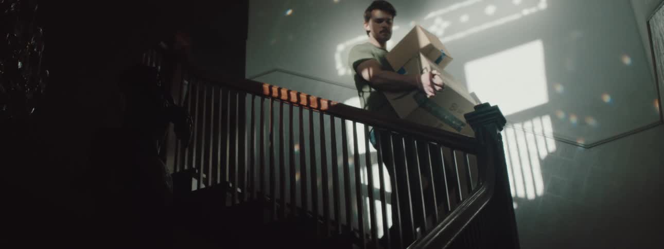 A man is carrying boxes and walking down some stairs