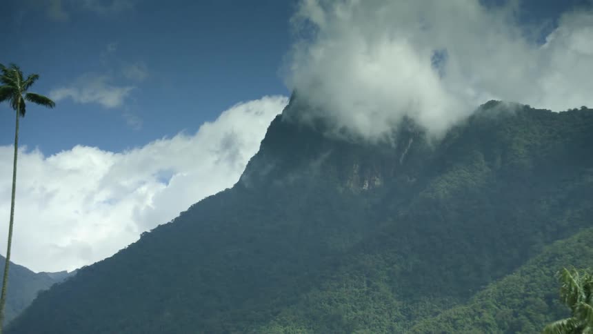 A landscape with trees and hills with the sky and clouds in the background