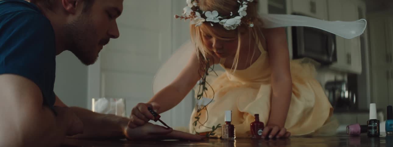 A girl is putting nail polish on her father