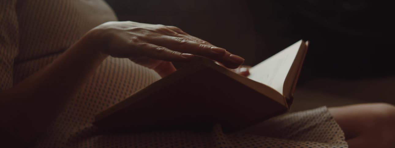 Woman with a white dress turns the pages of a book
