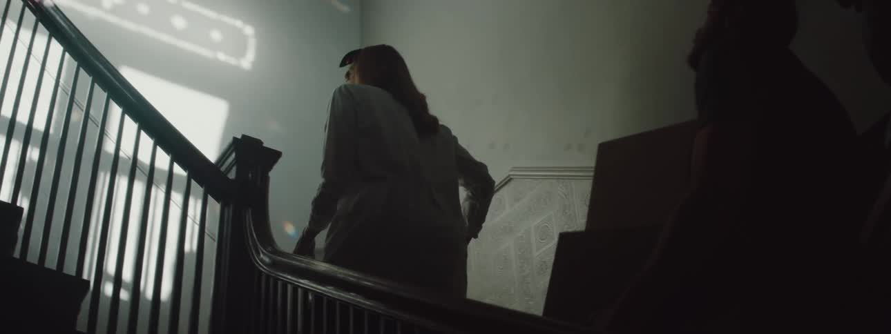 Woman carries a laundry basket up the staircase while a man carries boxes behind her
