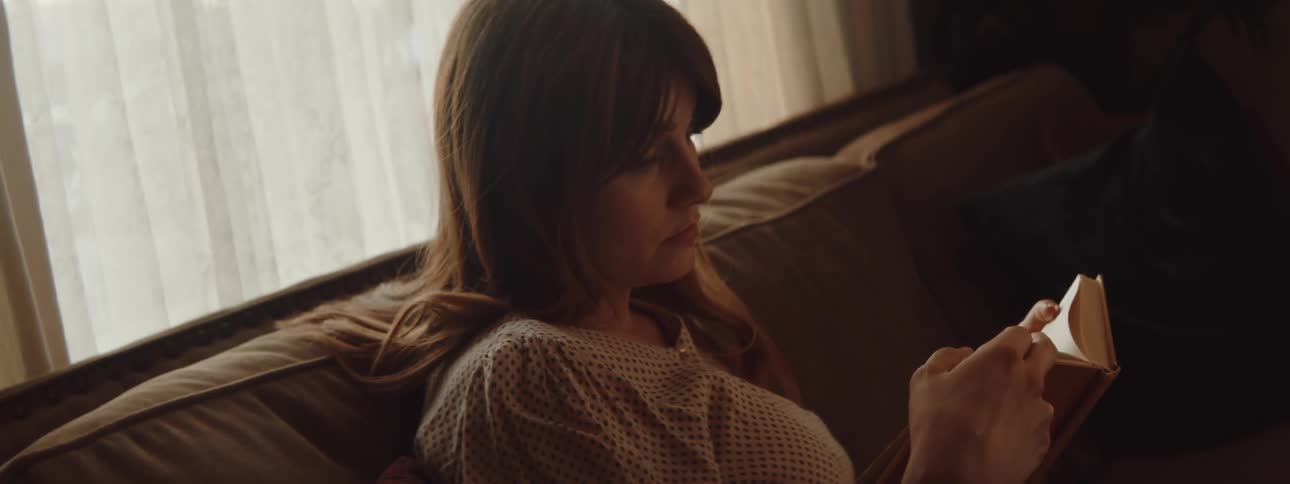 Woman sitting in a couch in the living room reads a book