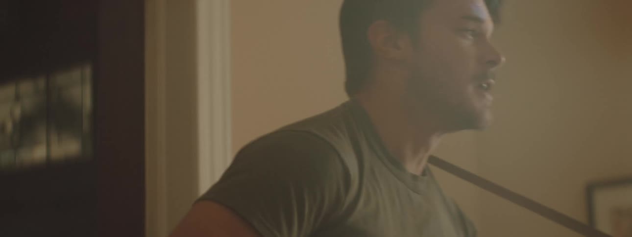 A man and a woman in a room dancing as the man plays a guitar