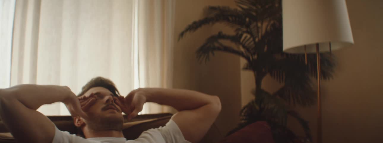 Man leans back in a chair as he rubs his eyes with his hands