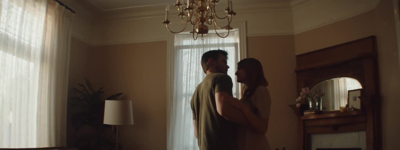 A wife and husband are dancing in a room together