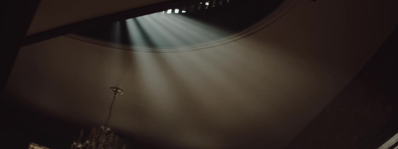 Sunlight casting down through windows onto a ceiling in a room with a chandelier