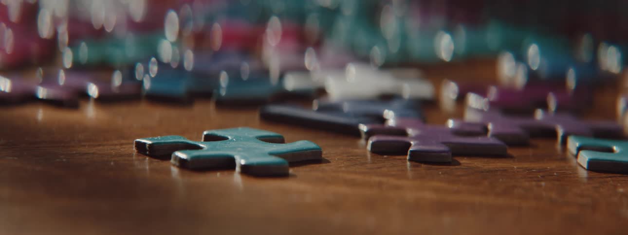 Jigsaw puzzle pieces on a table and fingers pick up a piece