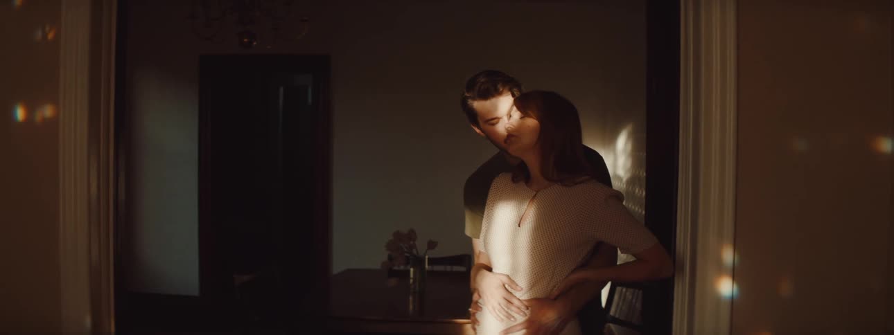 Husband is holding his wife close while standing by a door