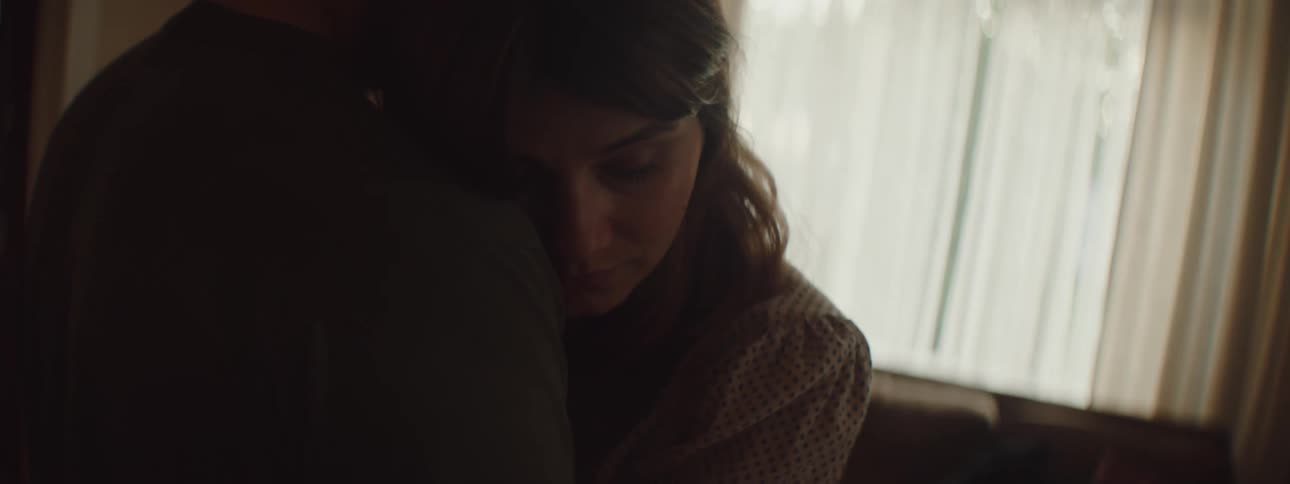 Man hugging a woman inside a dimly lit room at home