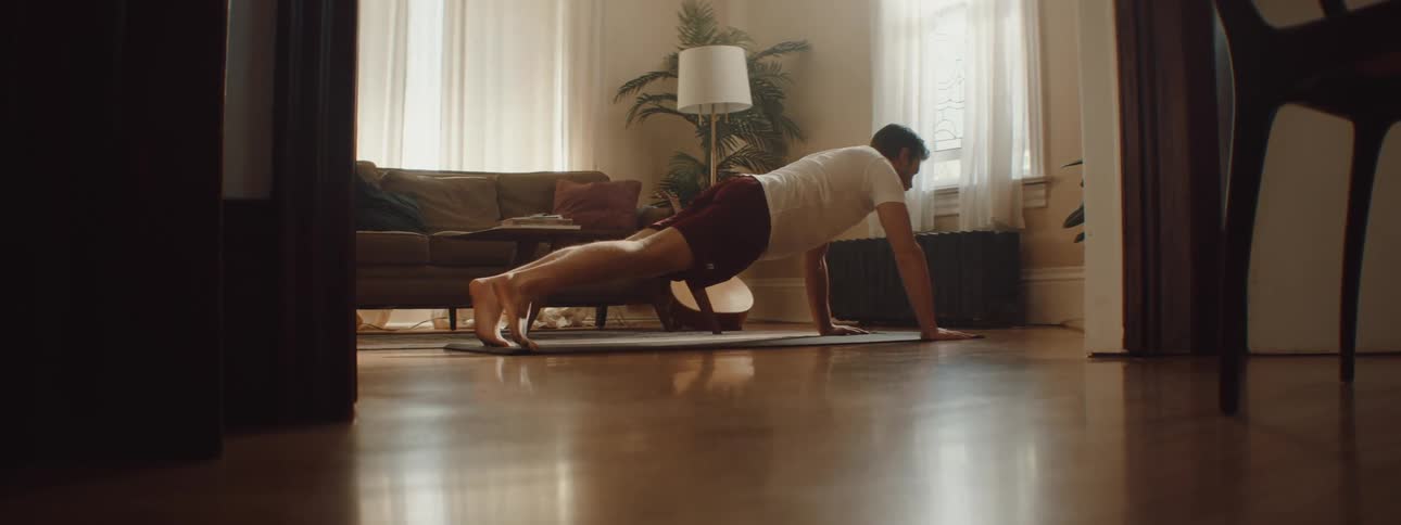 Man places a mat over the living room floor to exercise