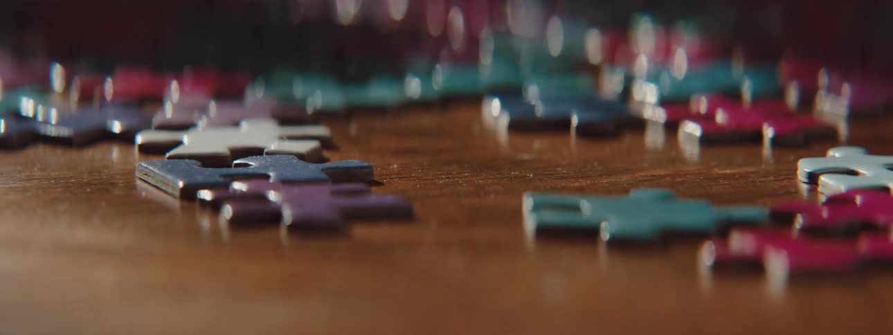Close up of womans hand picking up a puzzle piece